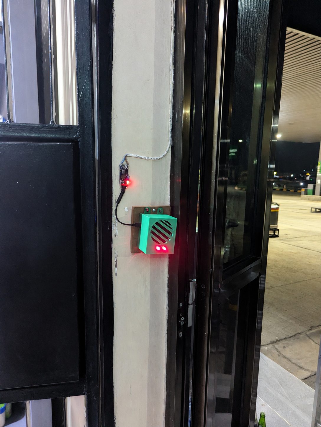 The speaker and sensor unit mounted at the entrance, with its status lights lit