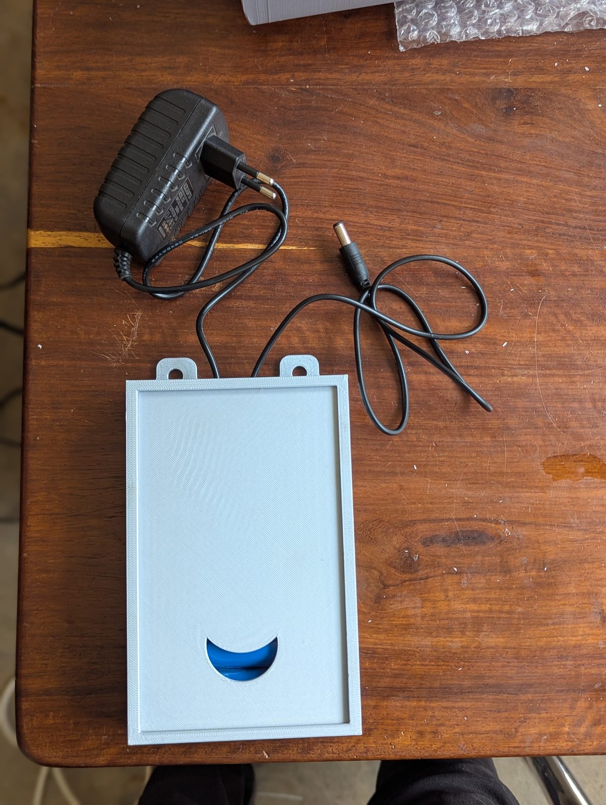 The custom 3D-printed battery backup pack built for the clock, with its power adaptor